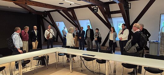 Mitglieder des VHV stehen in einem modernen Konferenzraum des Hauses Buhl mit sichtbaren historischen Fachwerkbalken.