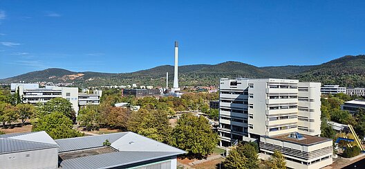 Blick über Gebäude und Grünflächen des Campus im Neuenheimer Feld vor den bewaldeten Höhen bei Heidelberg.