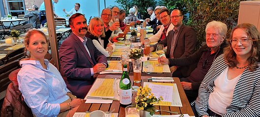 Teilnehmerinnen und Teilnehmer der VHV-Mitgliederausfahrt sitzen gemeinsam an einem langen Tisch beim Abendessen.